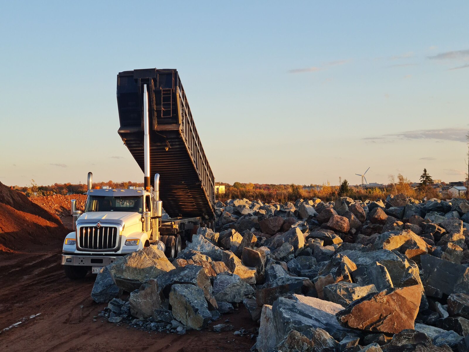 Tipper truck offloading aggregate at golden hour