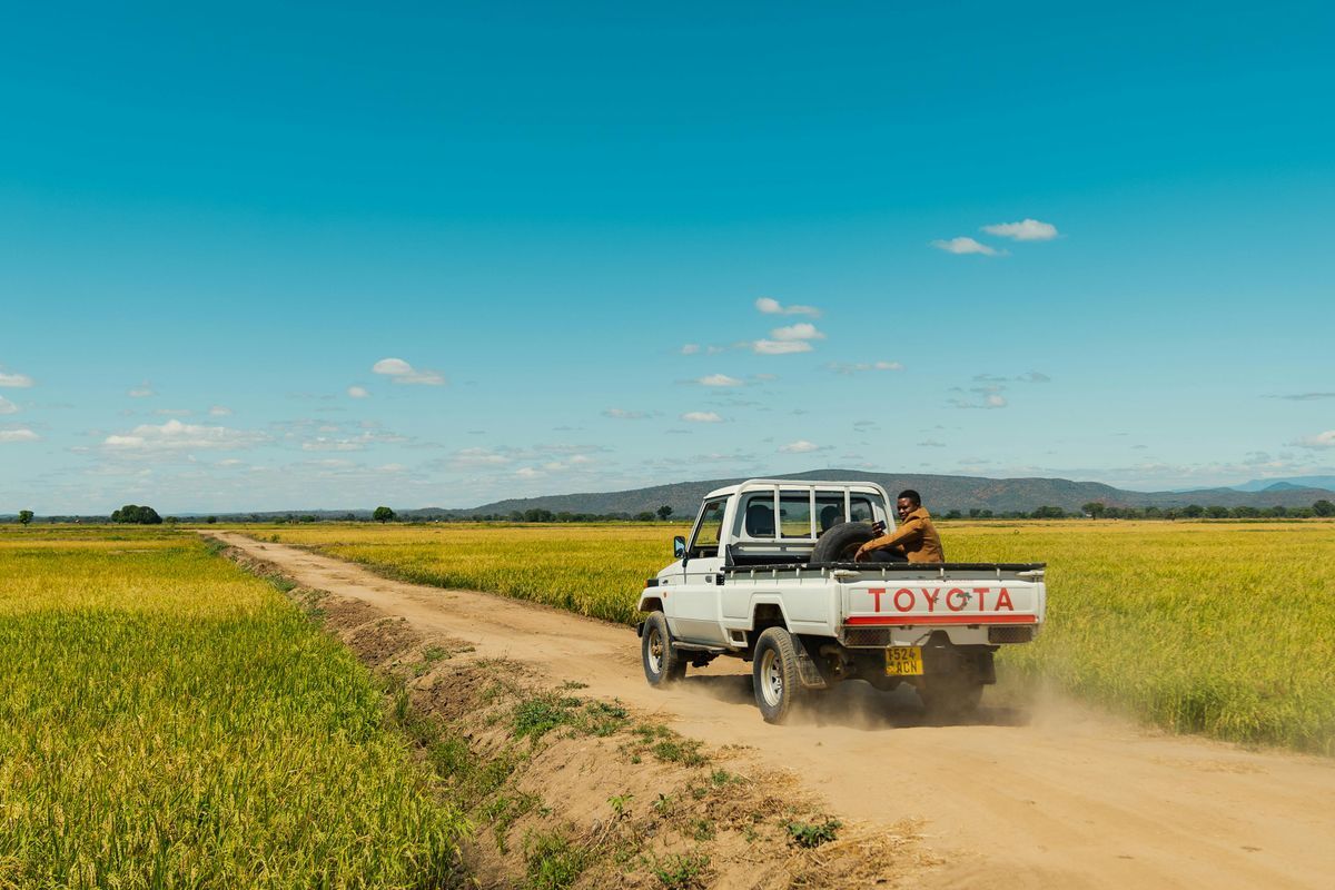 Vehicle travelling a farm road through green fields