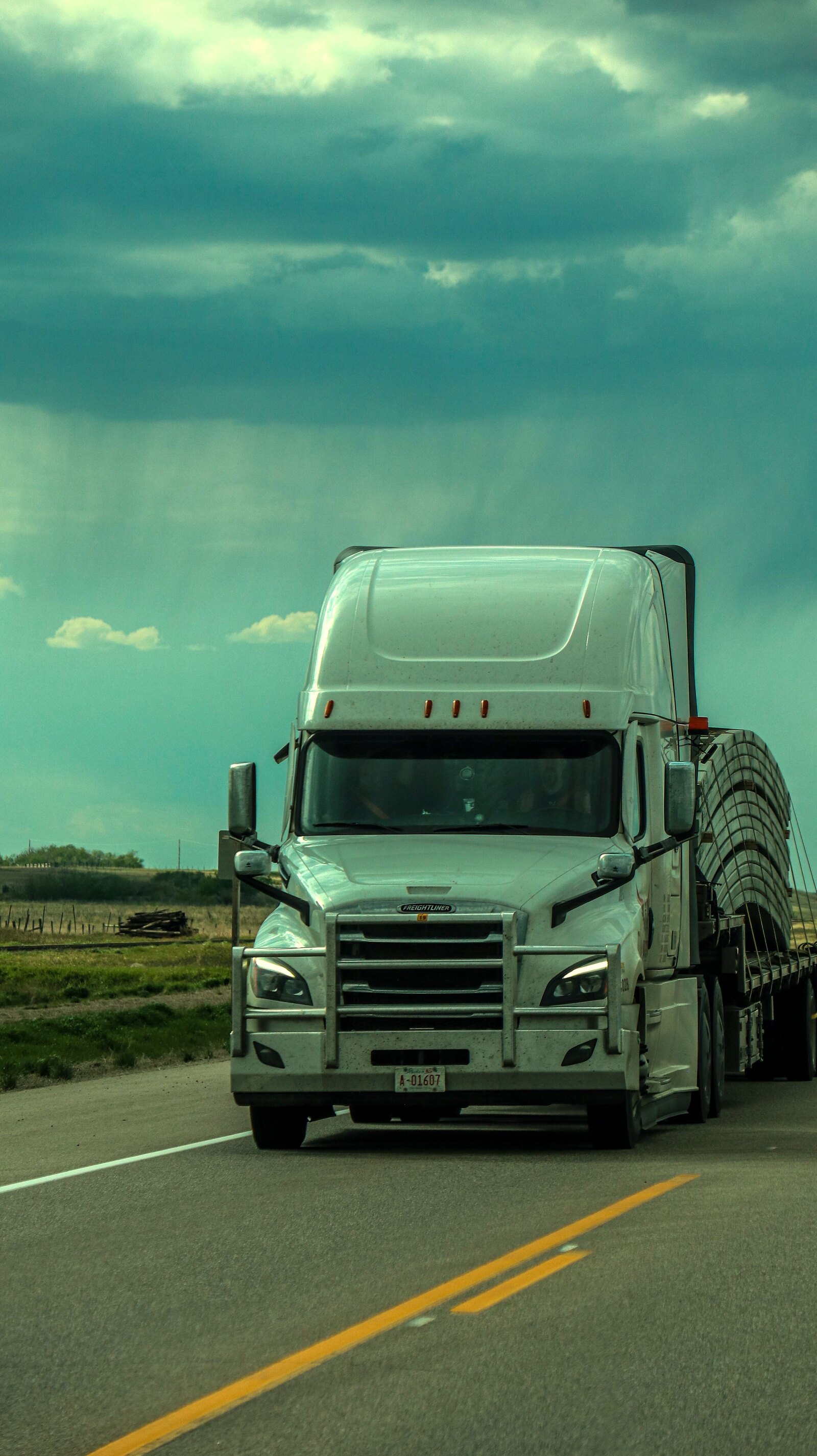 Freight truck on the highway beneath a dramatic storm sky